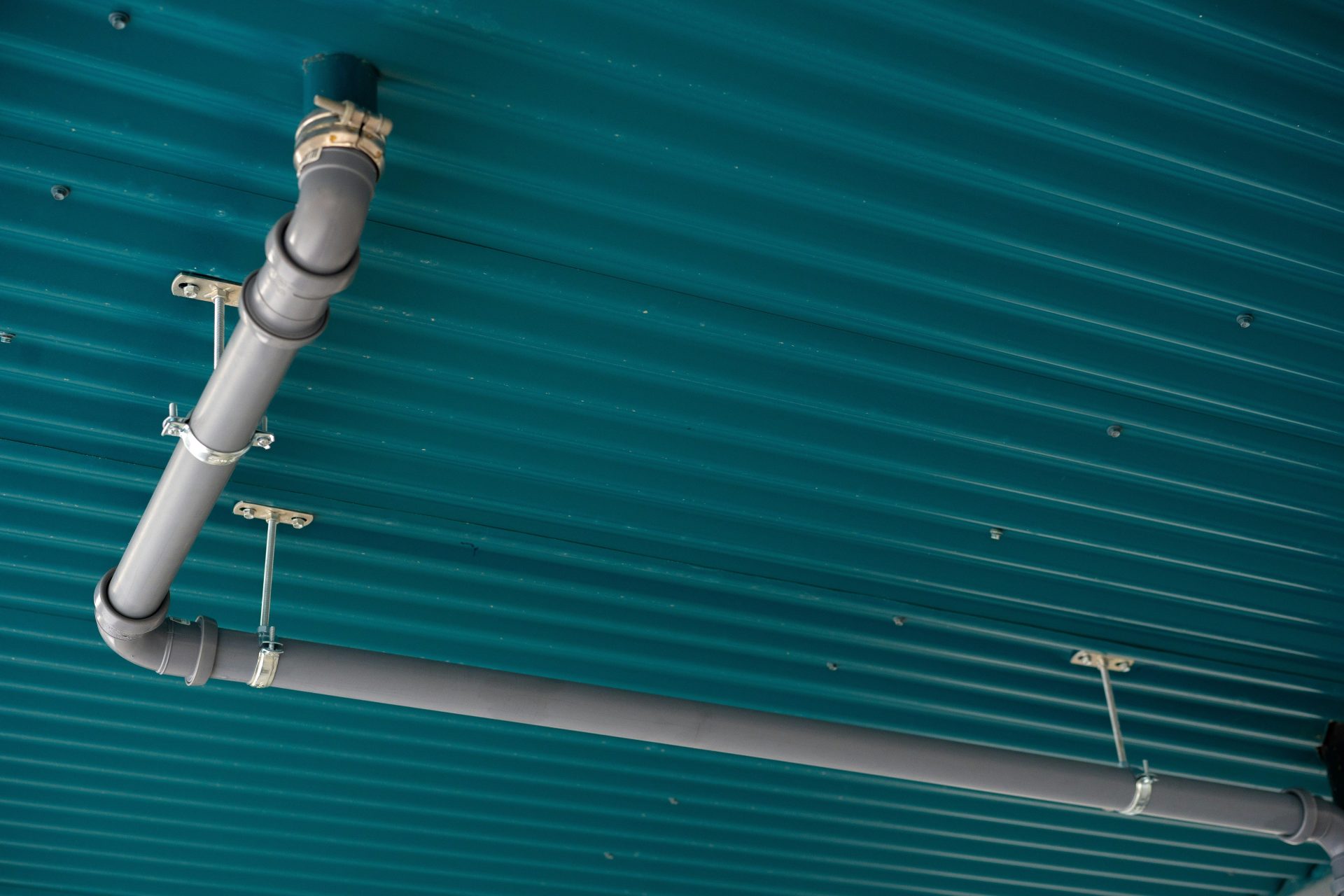 Pipes are installed on a teal, ribbed ceiling